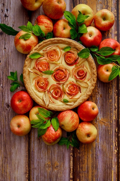 An apple pie baked on a wooden surface with fresh apples