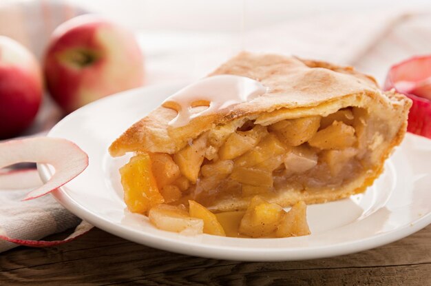 Apple pie piece on white plate on wooden background closeup