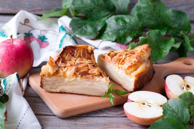 Apple pie and red apples on a wooden table