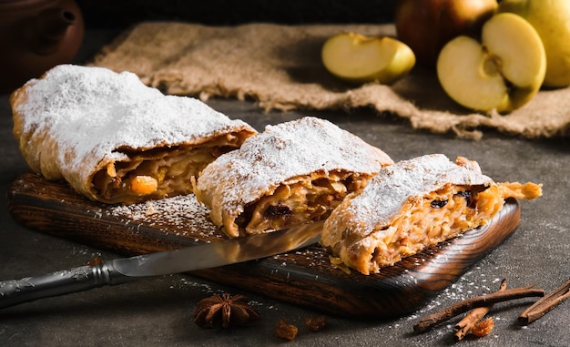 Apple pie - strudel or apfelstrudel, sliced ​​pie with apples and spices on a gray table, close-up, selective focus. Traditional pies of European cuisine