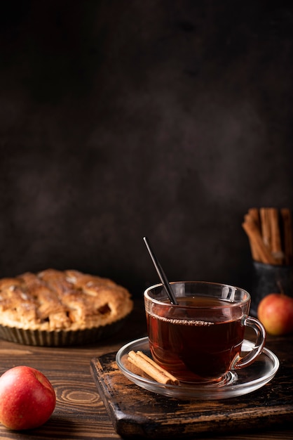 Apple pie with cinnamon and hot black tea on a wooden table