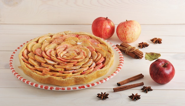 Apple pie with cinnamon on a plate and apples and cinnamon 