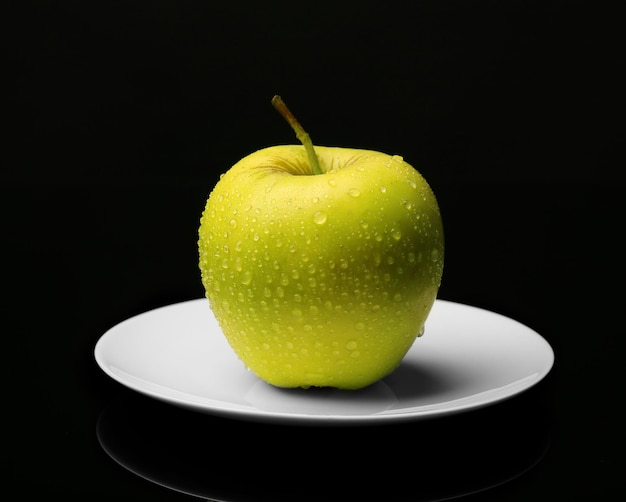 Apple on saucer on black background