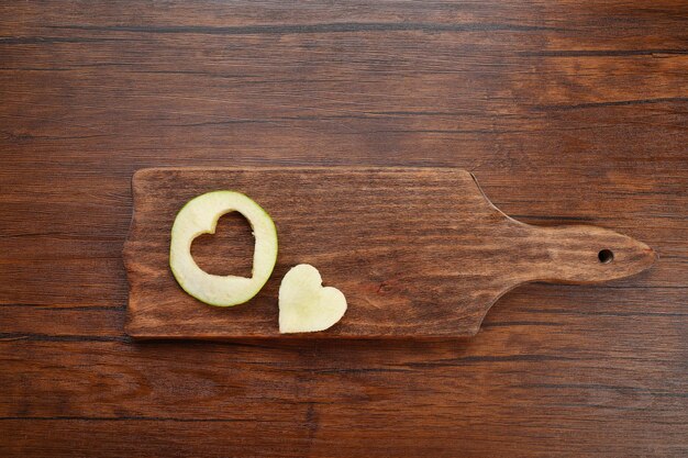 Apple slice with cut in shape of heart on wooden background