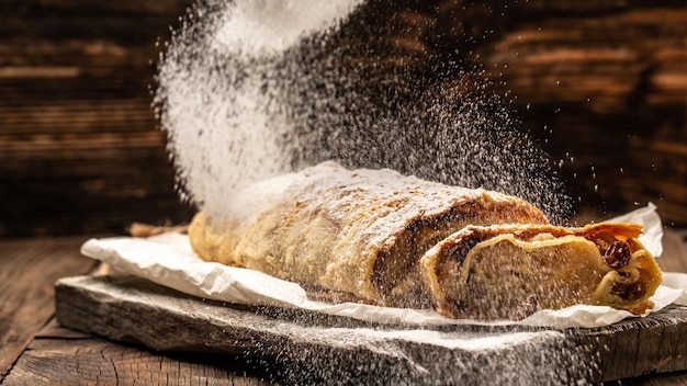 Apple strudel cake with cinnamon and raisins sieve sprinkling sugar powder from above austrian germany food