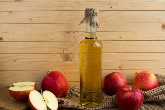 Apple vinegar cider in the glass bottle on the light brown wooden wall