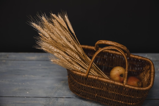 Apples and a bouquet of spikelets in a wicker basket on a wooden background scandinavian decorative elements of interior interior living room