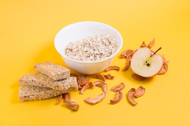 apples, oatmeal and oat bars on yellow background