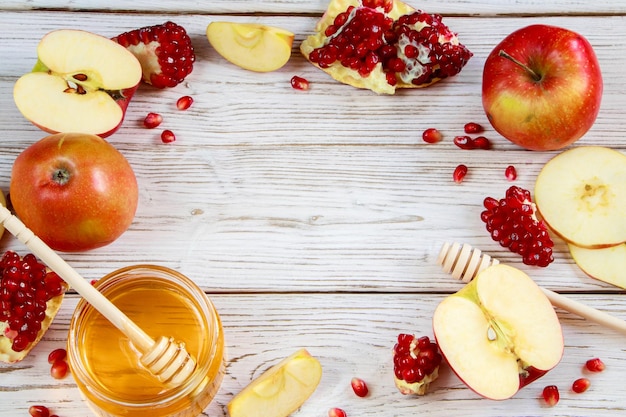 Apples pomegranates and honey on white wooden background Happy Rosh Hashanah Traditional symbols of the Jewish New Year celebration