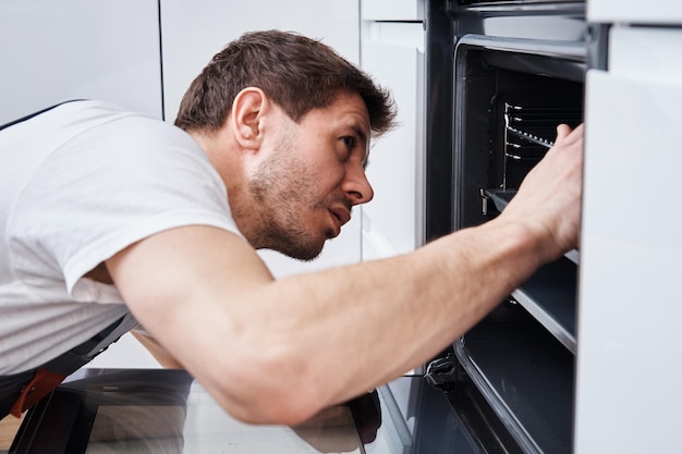 Photo appliance maintenance man fixing problem in the oven in kitchen