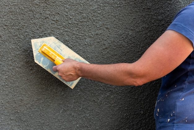 Application of decorative plaster on wall using construction tool.