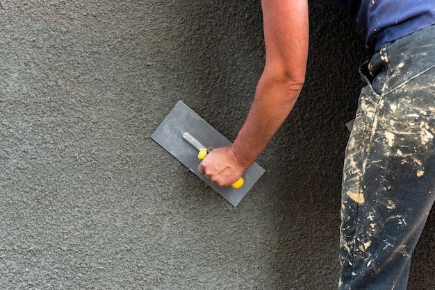 Application of decorative plaster on wall using construction tool.