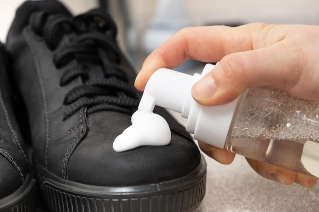 Photo applying cleaning foam from a bottle to nubuck men's shoes