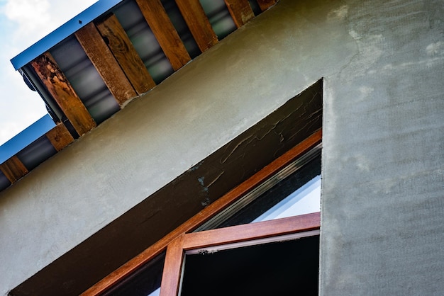 Applying fresh construction glue layer on insulated wall for covering fiberglass reinforcing mesh on mineral wool.