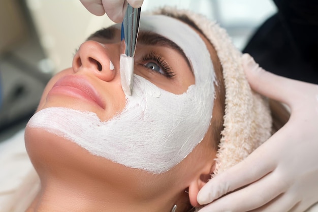 Applying a mask to the face in a beauty salon Cosmetologist and procedure for rejuvenation and moisturizing