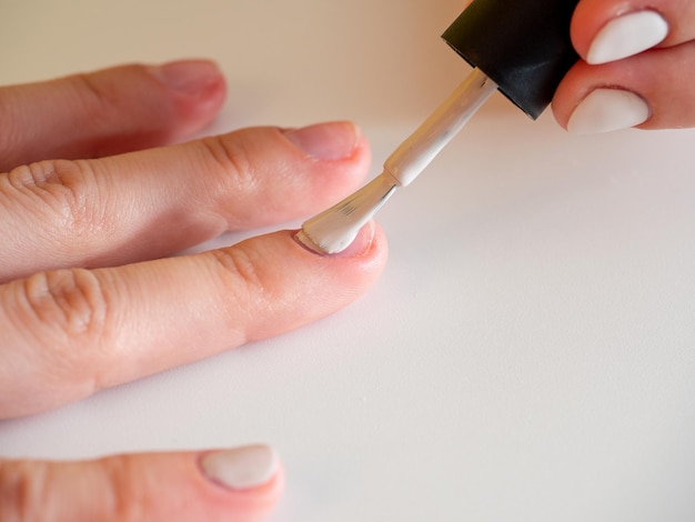 Applying white nail polish to the nail Manicure and nail care concept