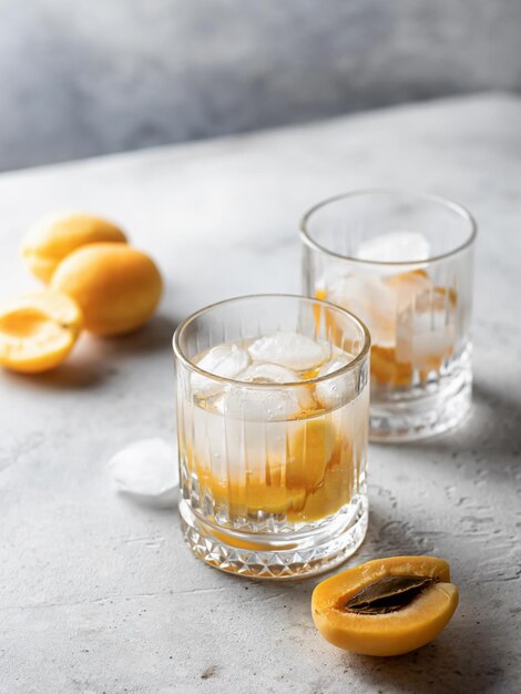 Apricot iced cocktails on gray background Refreshing summer alcoholic or nonalcoholic cocktails Detox infused water