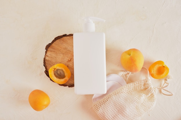 Apricots plastic white bottle with a dispenser for cream or soap, a wooden podium from a saw cut from a tree