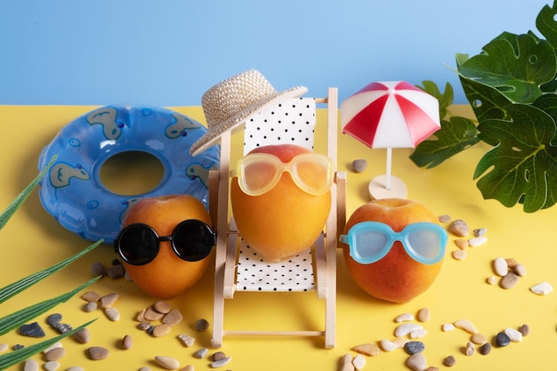 Apricots in sunglasses on the beach in a chaise longue and with inflatable circles