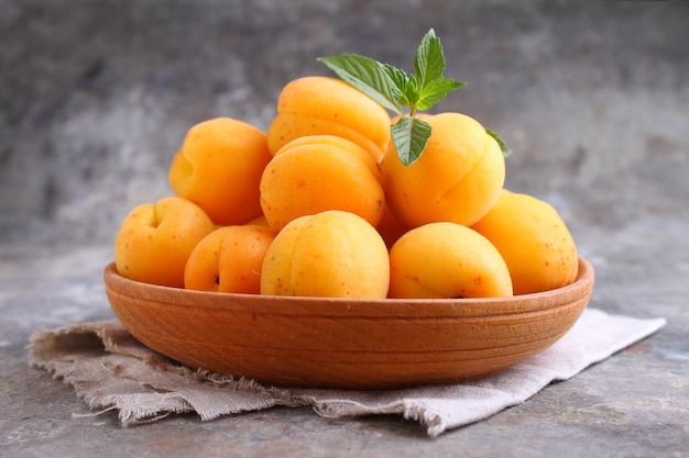 Apricots in a wooden plate with mint leaves