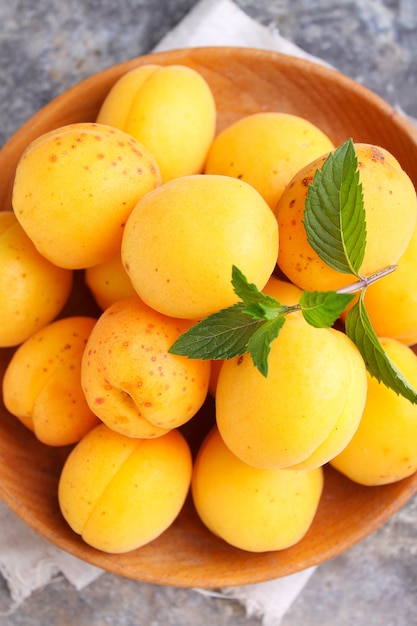 Apricots in a wooden plate with mint leaves