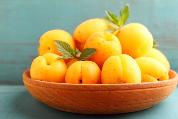 Apricots in a wooden plate with mint leaves