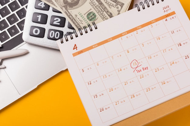 April of the year is Tax Day, closeup calculator, laptop computer, calendar, and Dollar money business finance budget concept