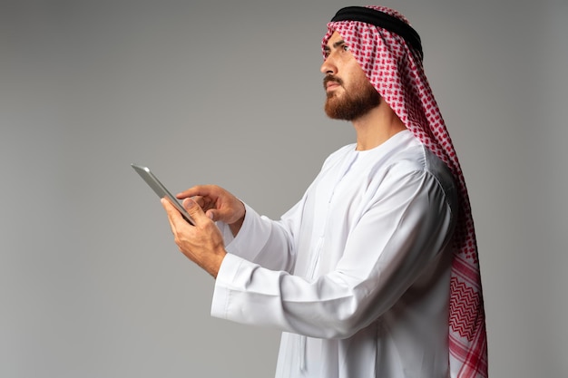 Arab businessman using digital tablet on gray background