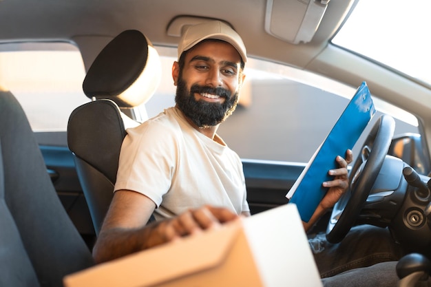 Arab delivery man looking at parcel box sitting in car