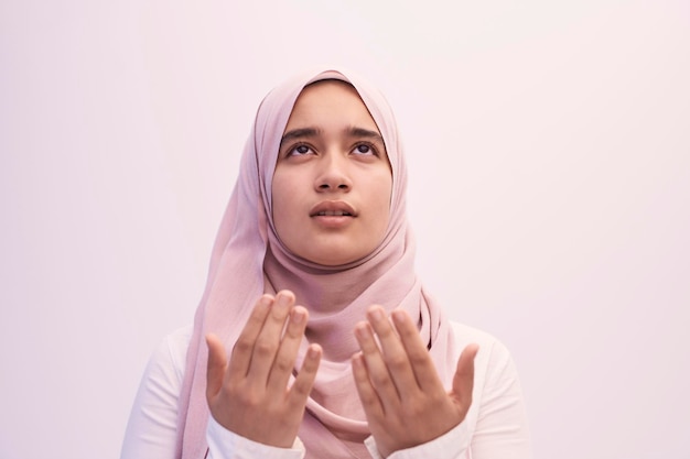 Arab female Muslim in traditional hijab clothes praying namaz dua open hands to Allah