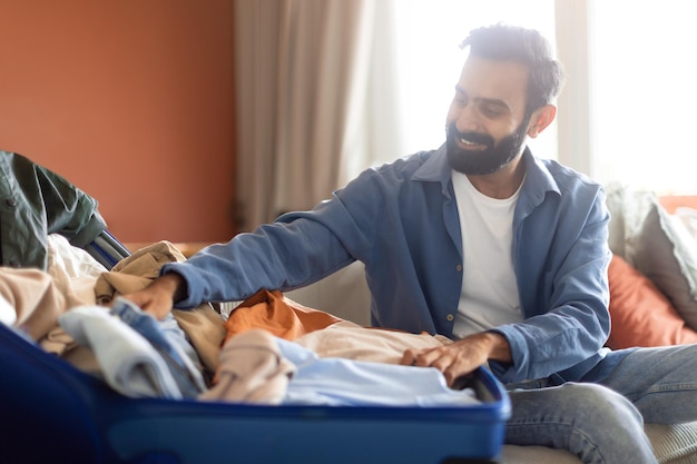 Arab guy preparing luggage for travel packing luggage suitcase indoor