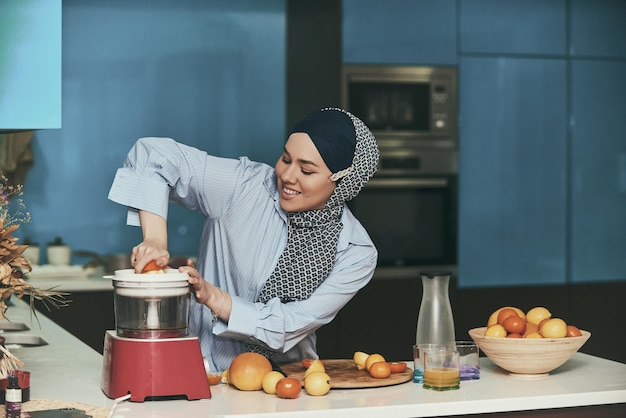 Arab hijab woman making fruit juice in the modern kitchen. Home concept. Healthy lifestyle concept. Selective focus. High quality photo.