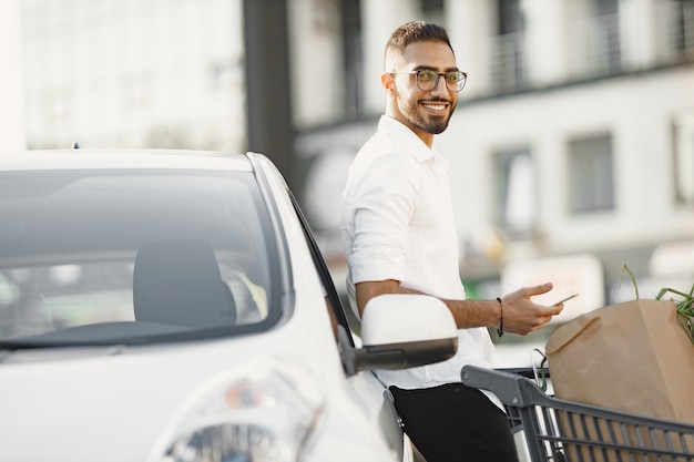 Arab man use smart phone while waiting for charging the battery in car.