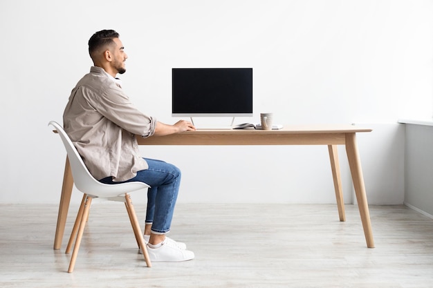 Arab man using computer with blank empty monitor