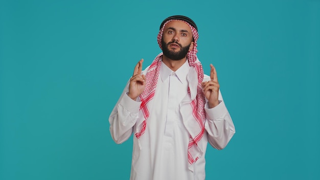 Arab person poses with fingers crossed