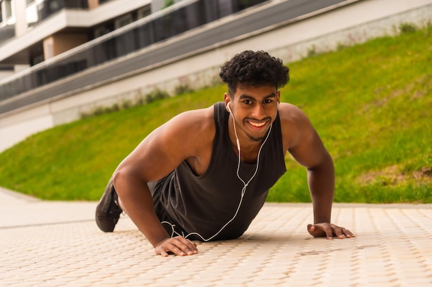 Arab strong young man doing sports in the city doing some pushups and looking at the camera