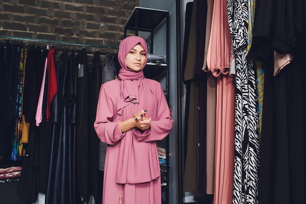 Arab woman in traditional muslim clothes buys a new dress in an oriental store