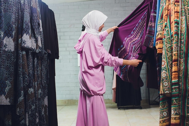 Photo arab woman in traditional muslim clothes buys a new dress in an oriental store