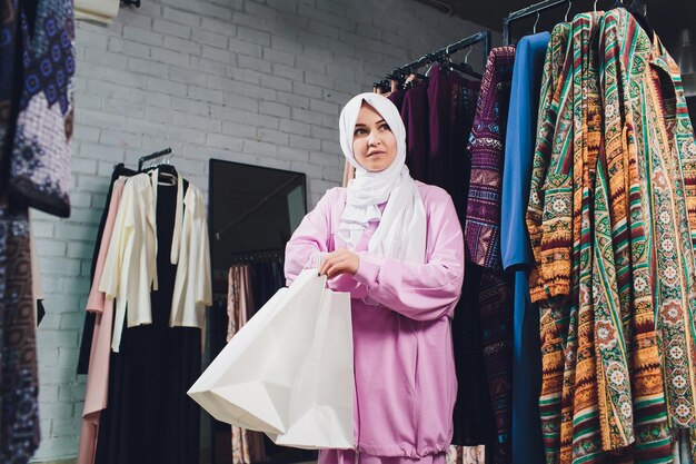 Photo arab woman in traditional muslim clothes buys a new dress in an oriental store