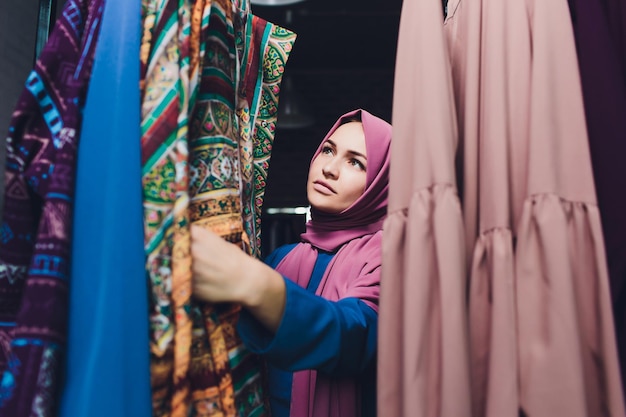 Photo arab woman in traditional muslim clothes buys a new dress in an oriental store