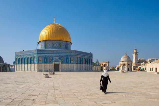 Arab woman with veil walking towards Dome of the Rock