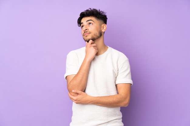 Arabian handsome man over isolated wall thinking an idea while looking up