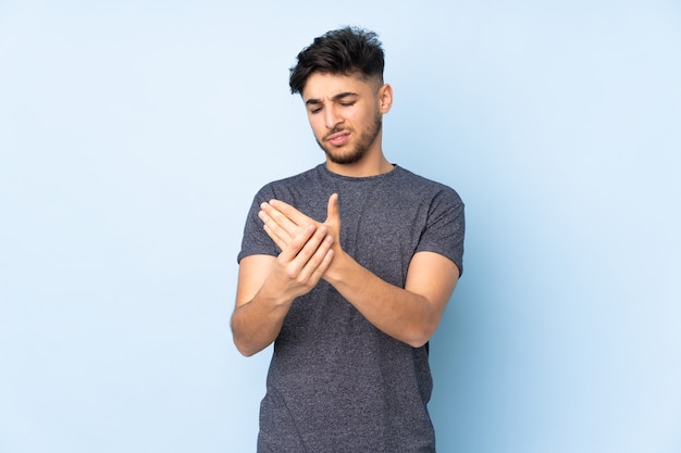 Arabian handsome man over wall suffering from pain in hands