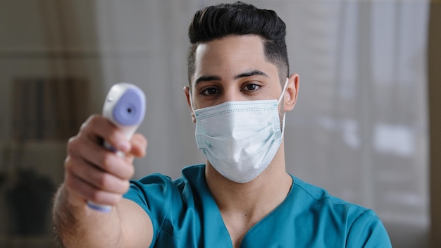 Arabian male medical worker doctor surgeon man in protective mask taking temperature with noncontact