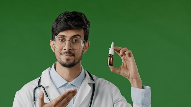 Arabian young male hispanic indian doctor in white coat in green studio recommend nasal spray