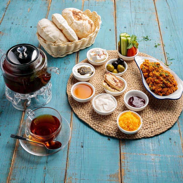 Arabic breakfast platter coffee bread salad sauce dip and pickle isolated on wooden table side view