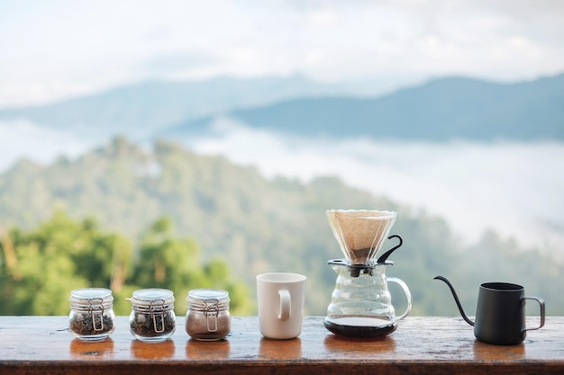 Arabica coffee brewing by Vintage coffee drip equipment set on wooden table in the morning with mountain and nature background