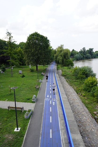 AradRomania  July 20 2021 Bicycle lane bike path in park people on electric scooters river