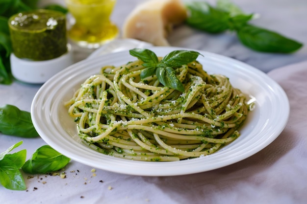 Photo araffy pasta with pesto sauce and basil leaves on a white plate generative ai