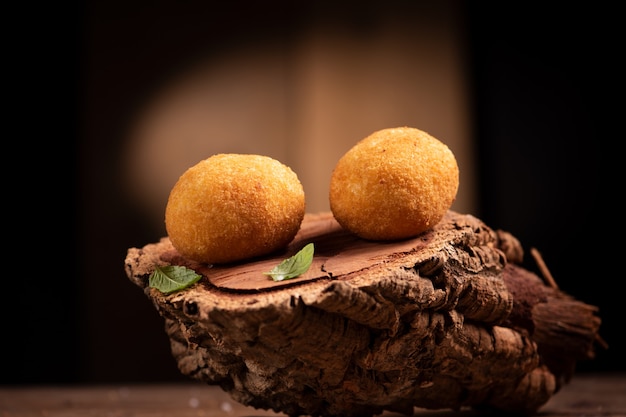 Arancini rice balls. Fried rice balls on brown wooden background. Snack, street food close up